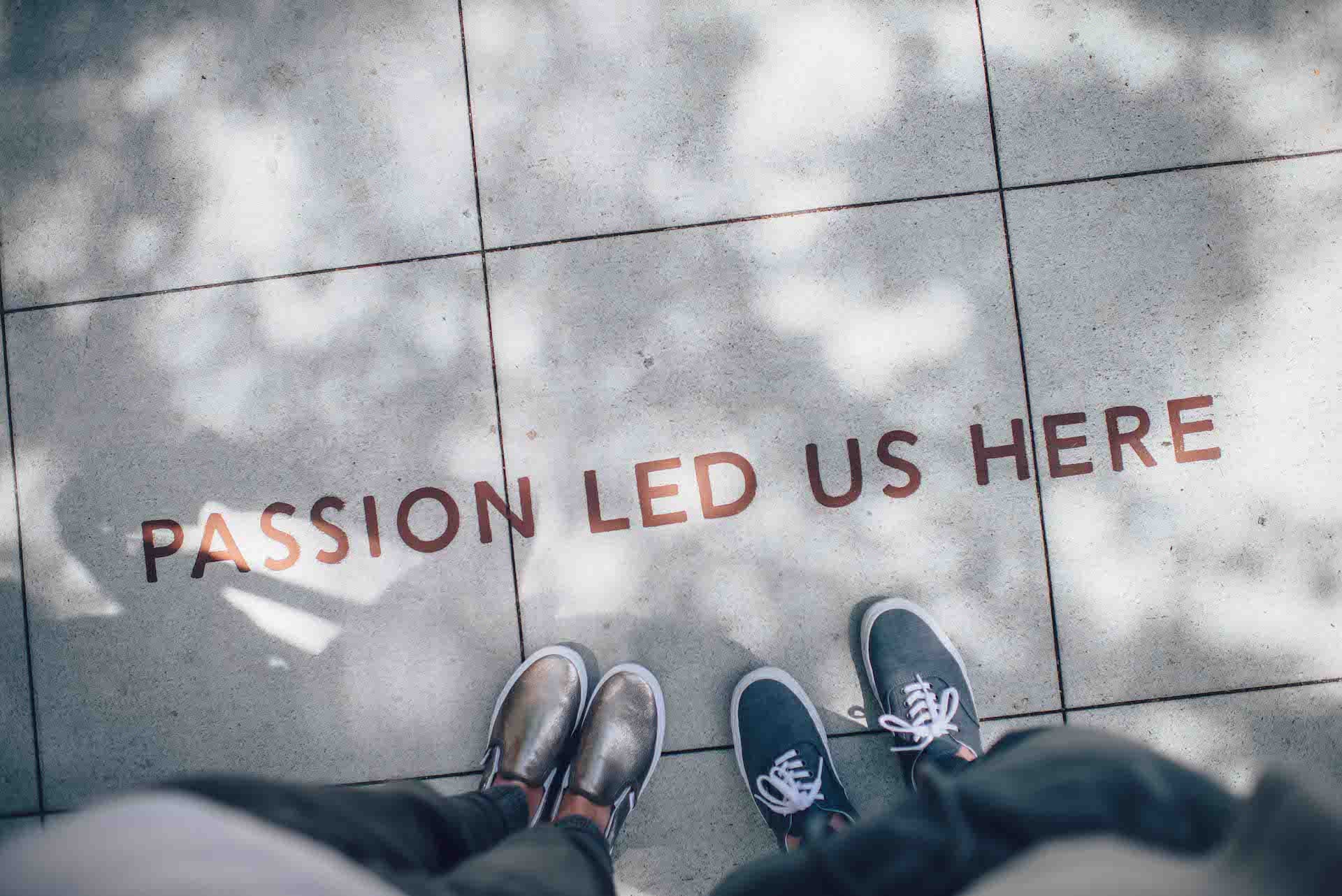 two people looking at a message written on the side walk saying passion led us here